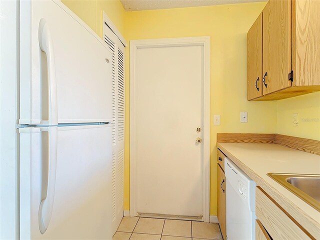 kitchen featuring white appliances, light countertops, a sink, and light tile patterned floors