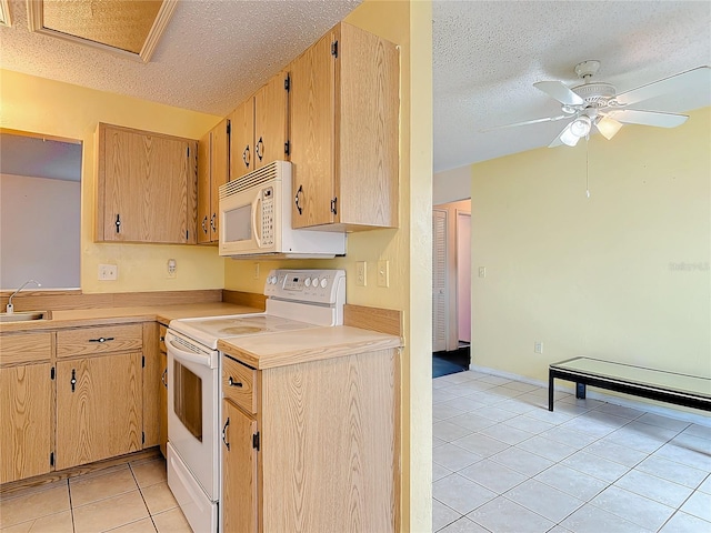 kitchen with white appliances, light tile patterned floors, light countertops, a textured ceiling, and a sink