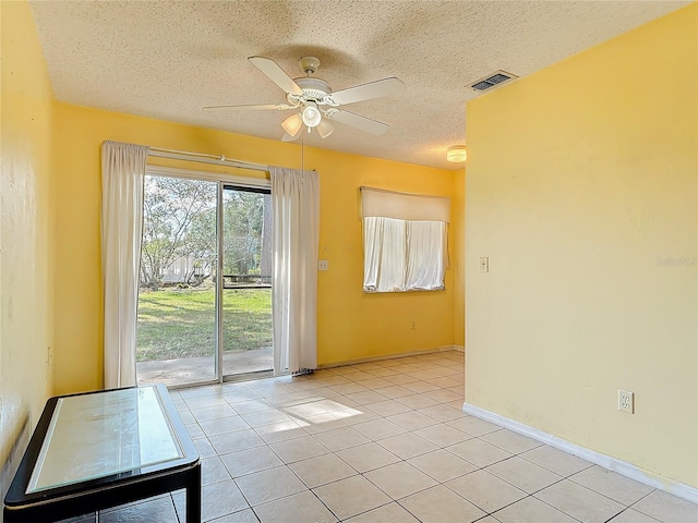 empty room featuring light tile patterned floors, a textured ceiling, visible vents, baseboards, and a ceiling fan