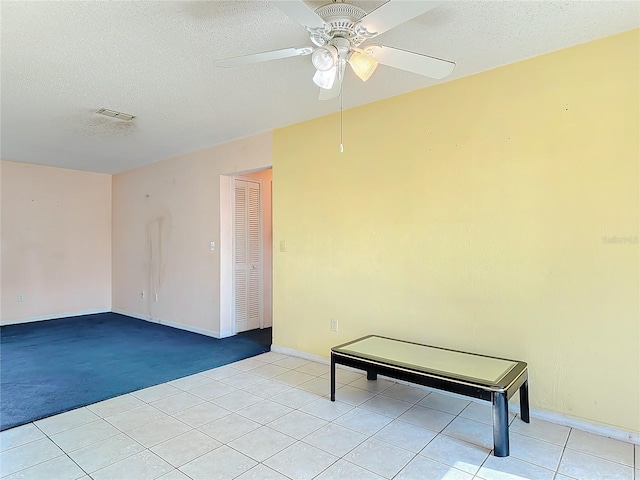 unfurnished room featuring a textured ceiling, light tile patterned floors, a ceiling fan, and baseboards