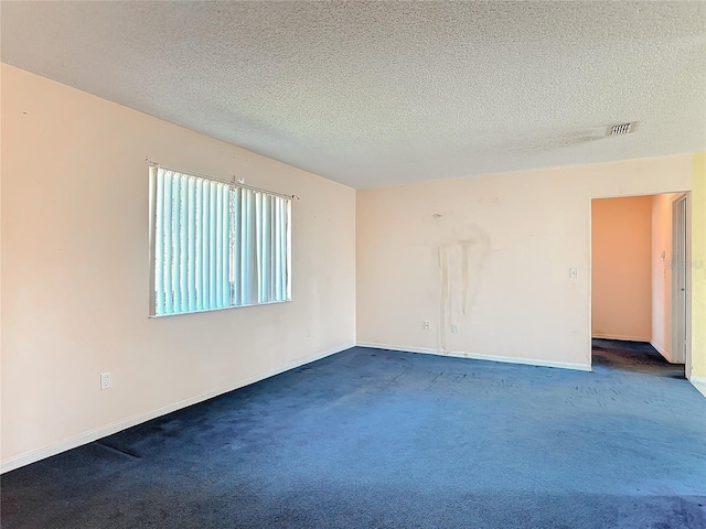 spare room with dark colored carpet, visible vents, a textured ceiling, and baseboards