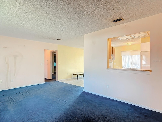 unfurnished room with carpet, visible vents, a textured ceiling, and baseboards