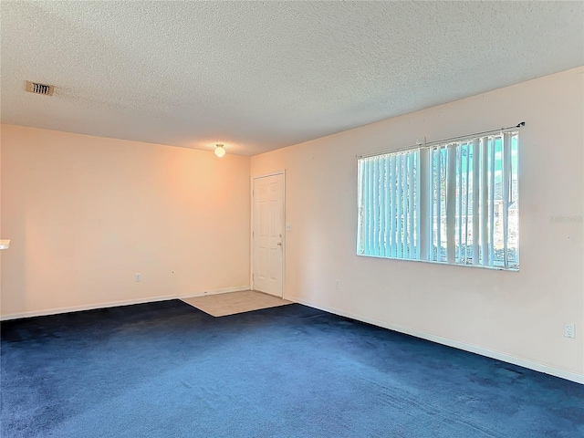 carpeted spare room with visible vents, a textured ceiling, and baseboards