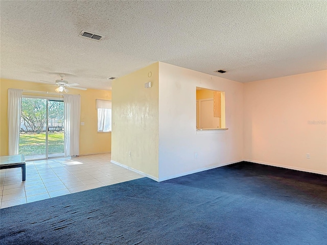 spare room with a textured ceiling, ceiling fan, visible vents, and light colored carpet