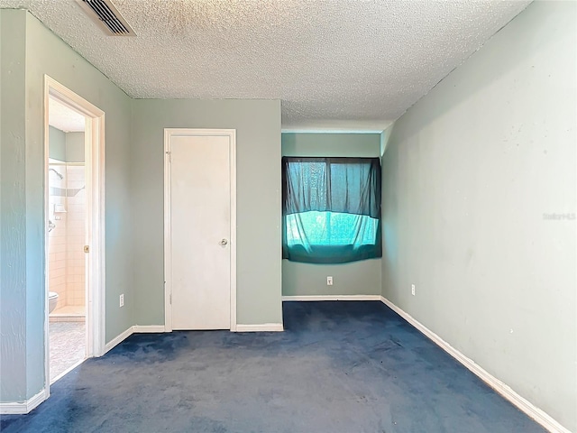 unfurnished bedroom featuring a textured ceiling, ensuite bath, visible vents, and baseboards