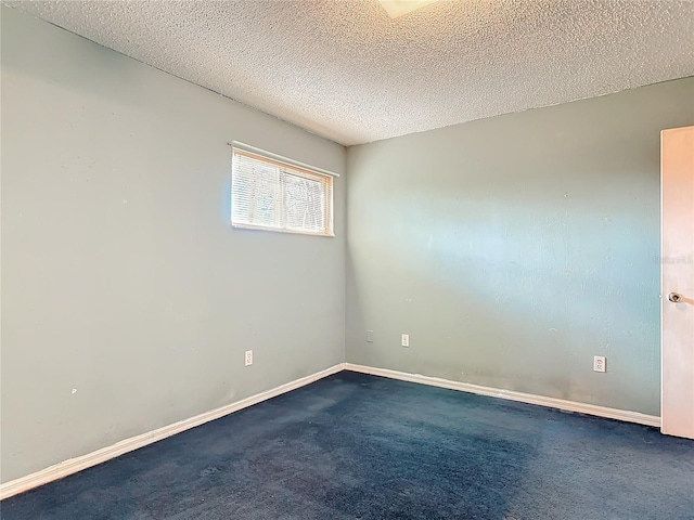 empty room with baseboards, dark colored carpet, and a textured ceiling