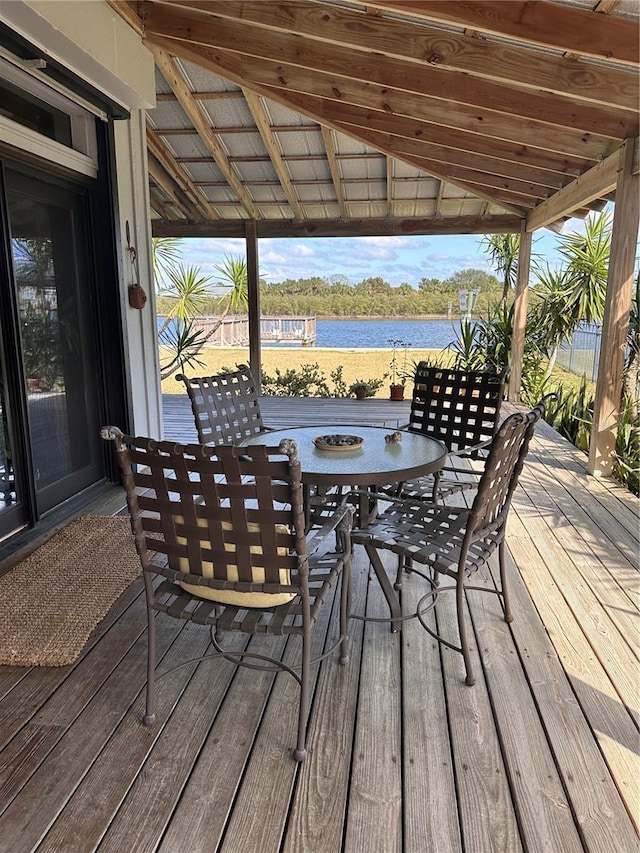 deck with outdoor dining area and a water view