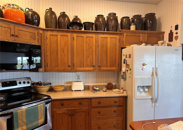 kitchen featuring white refrigerator with ice dispenser, brown cabinets, stainless steel electric stove, light countertops, and black microwave