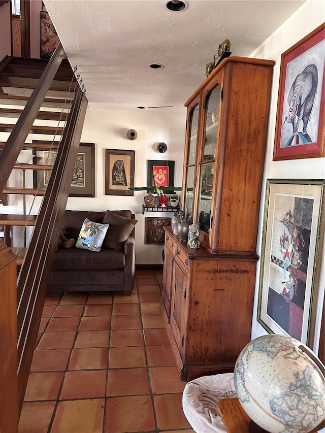 interior space featuring stairway, a textured ceiling, and dark tile patterned flooring