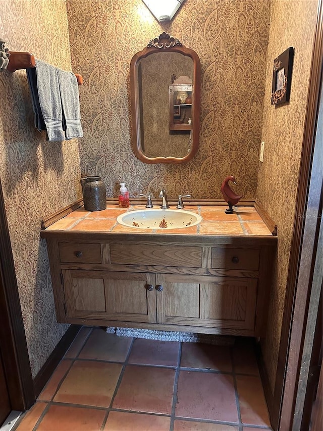 bathroom with wallpapered walls, vanity, baseboards, and tile patterned floors