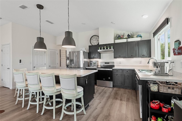 kitchen featuring visible vents, lofted ceiling, appliances with stainless steel finishes, light countertops, and a sink