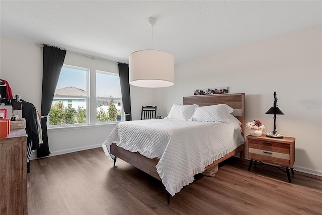 bedroom featuring a textured ceiling, wood finished floors, and baseboards