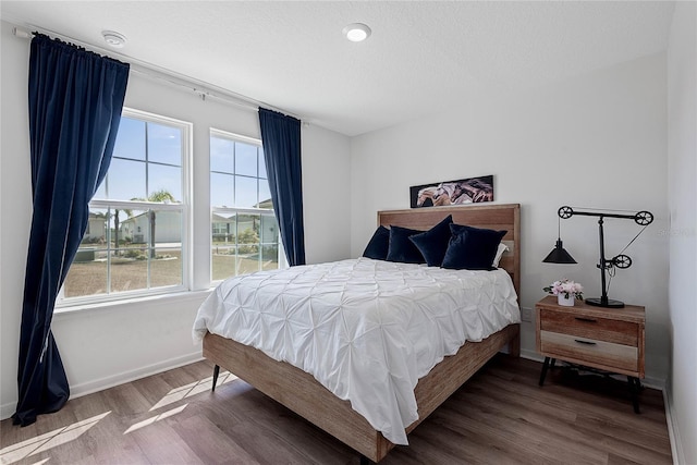 bedroom with multiple windows, a textured ceiling, and wood finished floors