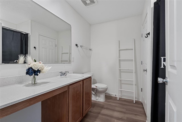 full bathroom with toilet, vanity, wood finished floors, and visible vents