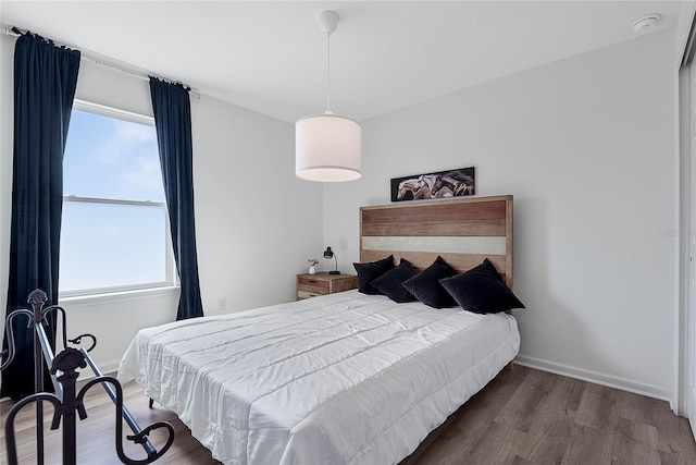 bedroom featuring multiple windows, baseboards, and wood finished floors