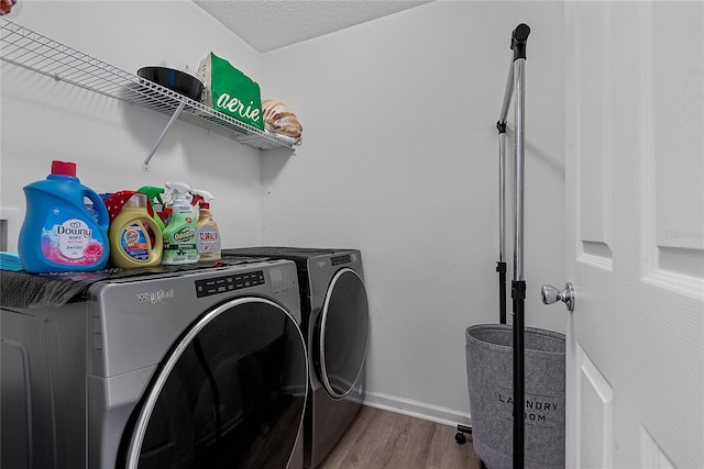 washroom featuring laundry area, baseboards, washer and clothes dryer, wood finished floors, and a textured ceiling