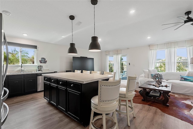 kitchen featuring a breakfast bar area, light wood-style floors, open floor plan, light countertops, and dark cabinetry