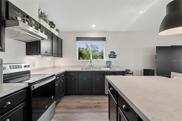 kitchen featuring light countertops, appliances with stainless steel finishes, a sink, a textured ceiling, and under cabinet range hood