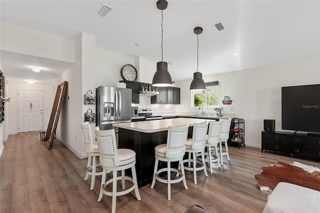 kitchen featuring stainless steel appliances, visible vents, light wood-style floors, light countertops, and a center island