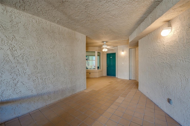 unfurnished room with tile patterned flooring, a textured wall, a textured ceiling, and ceiling fan