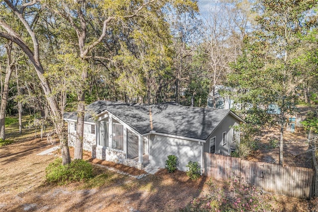 view of side of home with a shingled roof and fence