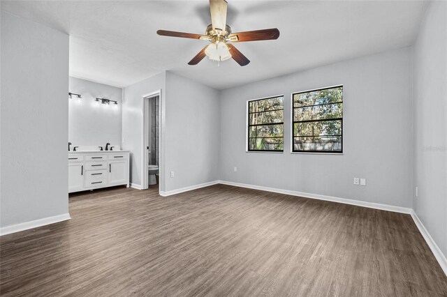 unfurnished bedroom featuring a sink, dark wood finished floors, a ceiling fan, and baseboards