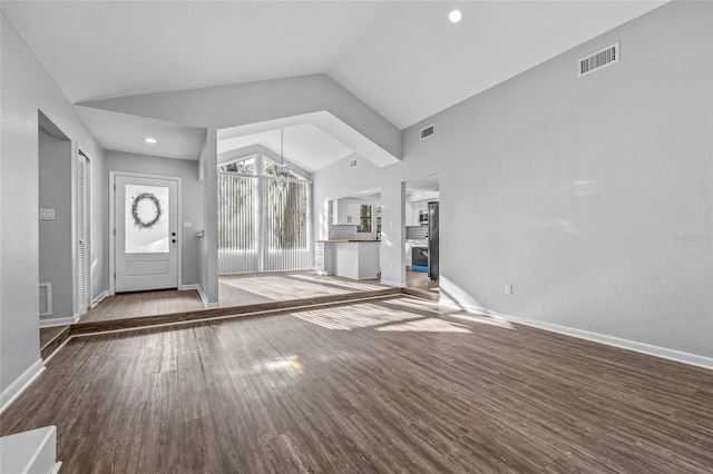 foyer entrance featuring lofted ceiling, visible vents, baseboards, and wood finished floors