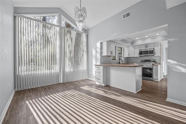 kitchen with lofted ceiling, stainless steel appliances, butcher block counters, visible vents, and backsplash