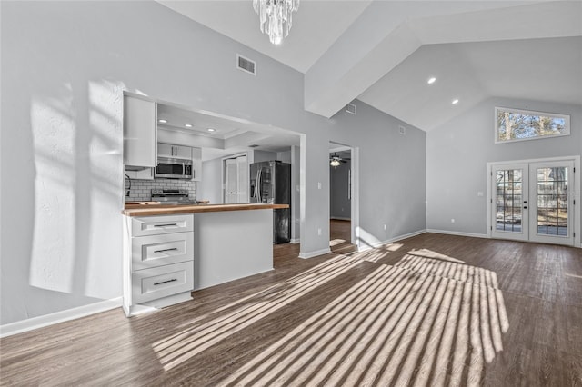 kitchen featuring visible vents, decorative backsplash, stainless steel appliances, white cabinetry, and wooden counters