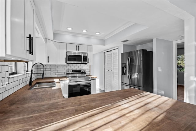 kitchen with a raised ceiling, visible vents, backsplash, appliances with stainless steel finishes, and a sink