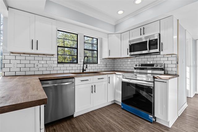 kitchen featuring stainless steel appliances, butcher block counters, a sink, decorative backsplash, and dark wood finished floors