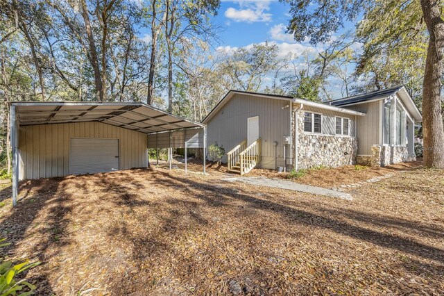 view of side of property featuring a garage, entry steps, driveway, and an outdoor structure