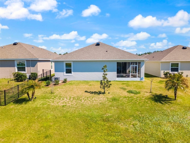 rear view of property with a sunroom, a yard, fence, and stucco siding