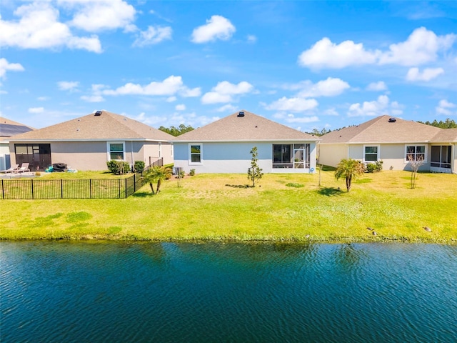 back of property featuring a water view, a sunroom, a fenced backyard, and a lawn