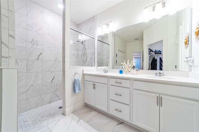 bathroom with a walk in shower, marble finish floor, double vanity, and a sink