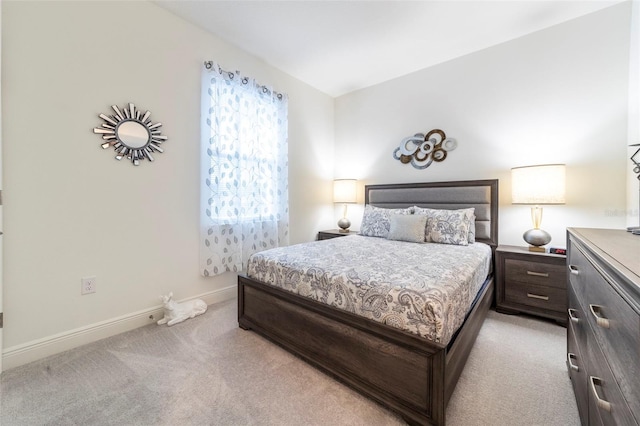 bedroom with light colored carpet and baseboards