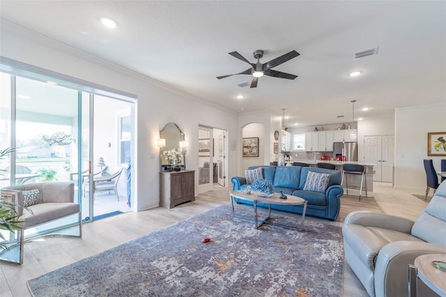 living area with arched walkways, ceiling fan, recessed lighting, visible vents, and crown molding