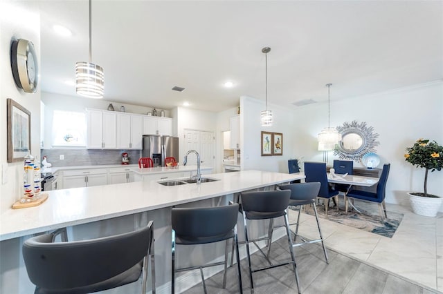 kitchen featuring a sink, visible vents, light countertops, tasteful backsplash, and stainless steel fridge