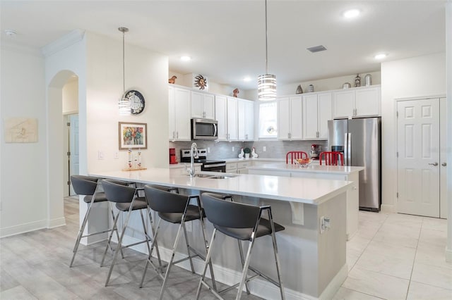 kitchen with arched walkways, light countertops, appliances with stainless steel finishes, a sink, and a peninsula