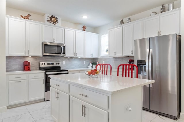 kitchen with white cabinetry, a kitchen island, appliances with stainless steel finishes, and tasteful backsplash