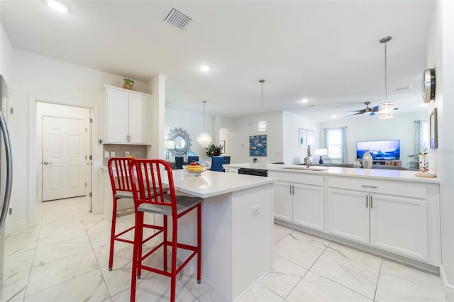 kitchen with visible vents, a kitchen island, a peninsula, marble finish floor, and light countertops