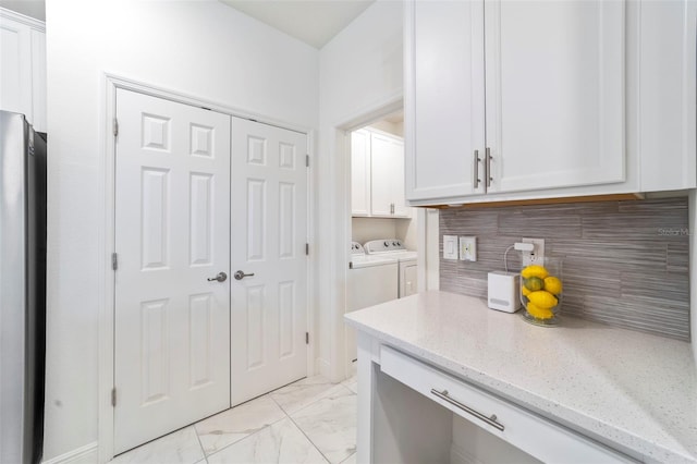 kitchen featuring marble finish floor, decorative backsplash, freestanding refrigerator, white cabinets, and separate washer and dryer