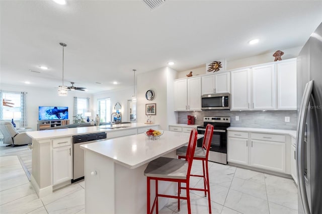 kitchen featuring appliances with stainless steel finishes, open floor plan, a peninsula, marble finish floor, and a sink