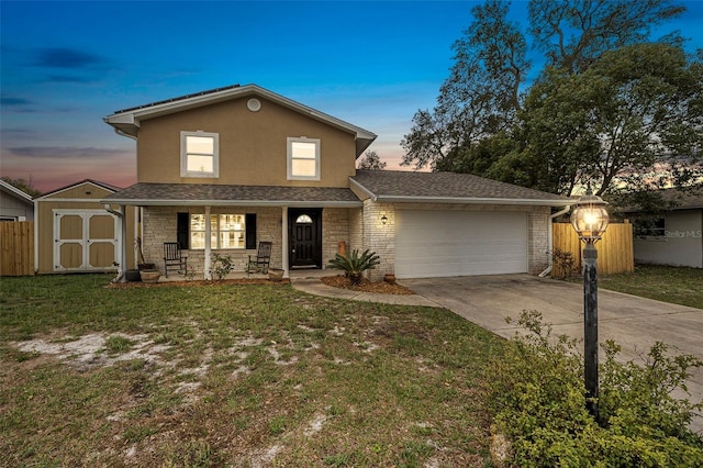 traditional home with an attached garage, covered porch, stone siding, driveway, and stucco siding