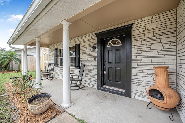 entrance to property with covered porch and brick siding