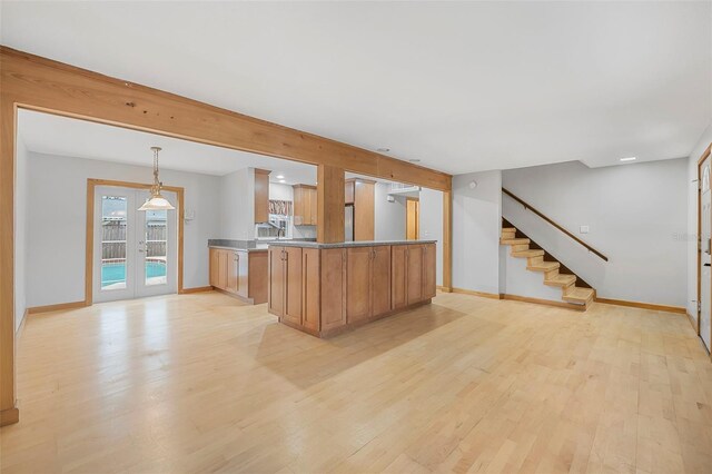 kitchen with open floor plan, decorative light fixtures, light wood finished floors, and french doors