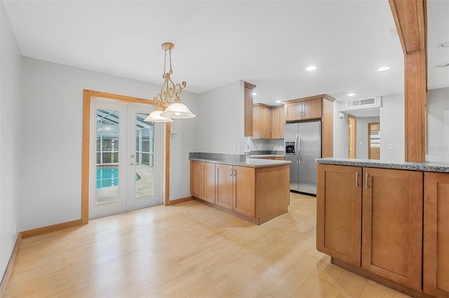 kitchen featuring a peninsula, french doors, brown cabinetry, and stainless steel fridge