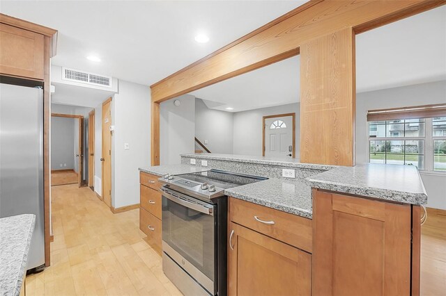 kitchen with light stone countertops, visible vents, stainless steel appliances, and light wood-style floors