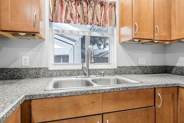 kitchen featuring brown cabinetry, light countertops, and a sink