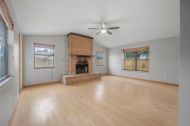 unfurnished living room featuring lofted ceiling, ceiling fan, a textured ceiling, a brick fireplace, and light wood finished floors